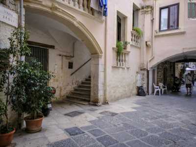 Attraversiamo l'arco per accedere alla corte con classica pavimentazione a basole bianche e nere. Qui si affacciano due edifici prospicenti: Palazzo Zeuli a sinistra...